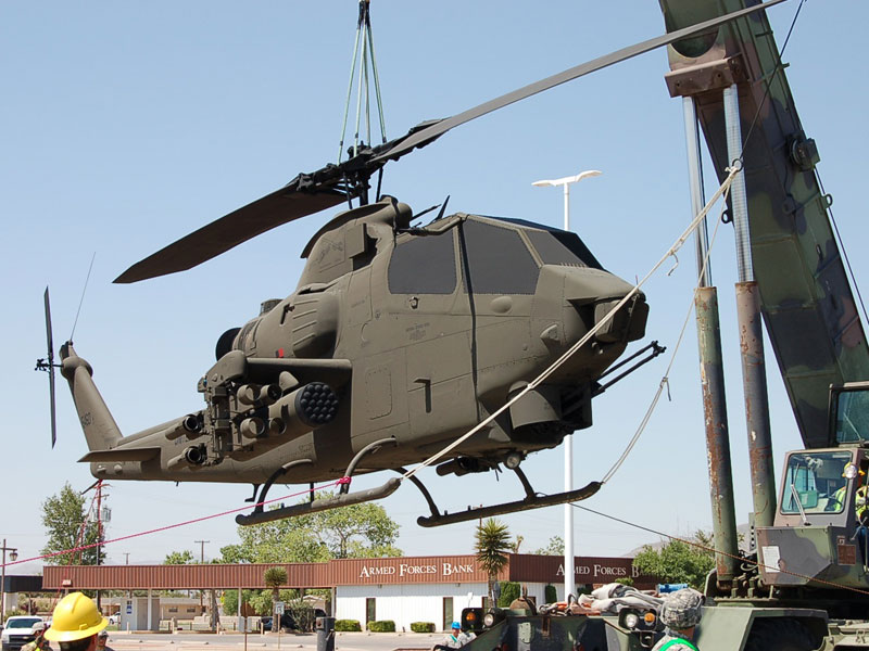 A US Army helicopter being transported by a crane outside of Fort Bliss and Old Ironsides Musuems.